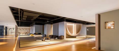 A modern interior with a wooden floor, a seating area with cushions, and a large illuminated structure.