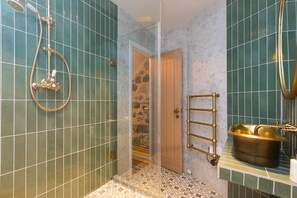A bathroom with a shower, a sink with a gold basin, and a towel rack. - She Sells Sanctuary,St Ives–Sleeps 6–Sea View–Woodburner–Roll Top Steel Bath (St Ives)