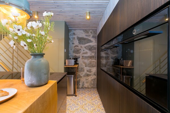Una cocina moderna con pared de piedra, armarios de madera y un ventanal grande.