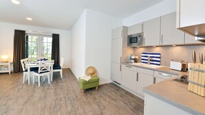 Cocina moderna con armarios blancos, microondas y encimera de madera.