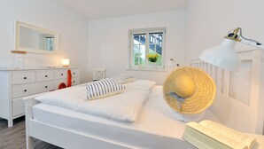 Un dormitorio con cama, lámpara de noche, ventana con vistas, cómoda y espejo.