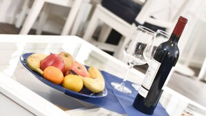 A dining table with a fruit platter, wine bottle, and glasses. - Comfortable vacation apartment with sea view and terrace in the Blue House in Ralswiek (Ralswiek)