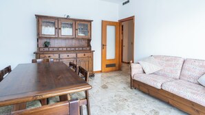 Un coin repas avec une table et des chaises en bois, un canapé à motifs et un meuble avec des portes en verre.