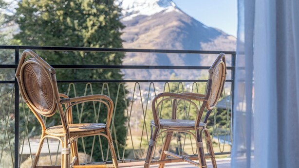 Deux chaises en osier sur un balcon avec vue sur la montagne.