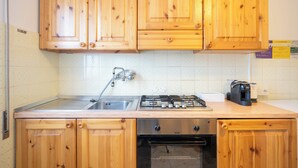 Une cuisine avec des meubles en bois, un évier en acier inoxydable, une cuisinière à gaz et un four.