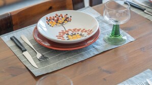 Une table à manger dressée avec des assiettes, des couverts et un verre.