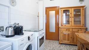 Uma cozinha com máquina de lavar, cafeteira e armário com portas de vidro.