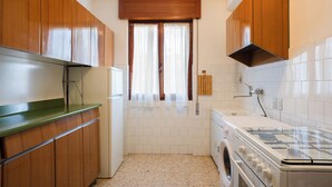Una cocina funcional con armarios de madera, horno integrado y lavadora.