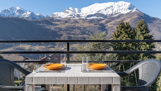 Een tafel met twee oranje borden en een glas water, met een berg op de achtergrond.