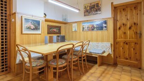 Un comedor con una mesa y sillas de madera, un banco y una puerta de madera.