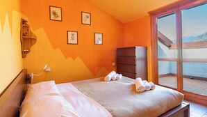 Un dormitorio con cama, cómoda y ventana con vistas a las montañas.