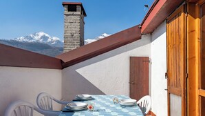 Una mesa de comedor con platos y vasos, sillas blancas y vistas a montañas nevadas.