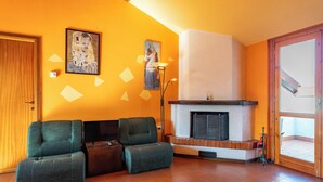 Una sala de estar con chimenea, dos sofás verdes y una puerta de madera.