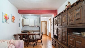 A compact living space with a kitchen, dining area, and a wooden cabinet unit. - The Court of the moon (Barzio)