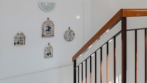 A staircase with a wooden handrail and metal balusters, leading to a landing with white walls and a granite floor. - The Court of the moon (Barzio)