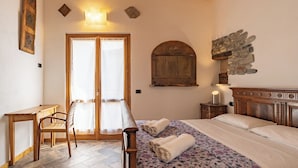 A bedroom with a bed, a desk, a chair, a stone wall, and a wooden ceiling. - Ballabio Lake - Rustic Chic Retreat (Ballabio)