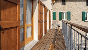 A wooden balcony with a stone wall and green shutters, overlooking a mountainous area. - Ballabio Lake - Rustic Chic Retreat (Ballabio)