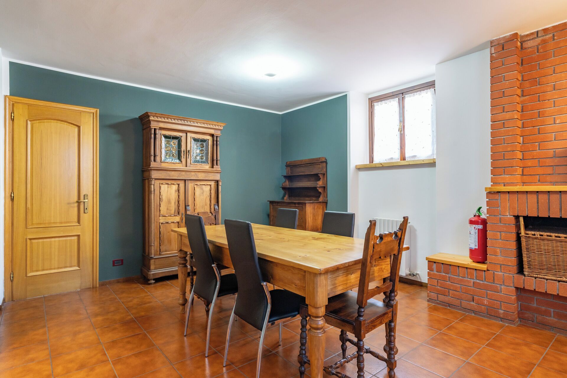 Un comedor con mesa y sillas de madera, un armario de madera y una chimenea de ladrillo.