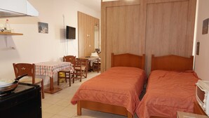 Ein Zimmer mit zwei Betten, einem Esstisch mit Stühlen, einem Fernseher und einer Mikrowelle.