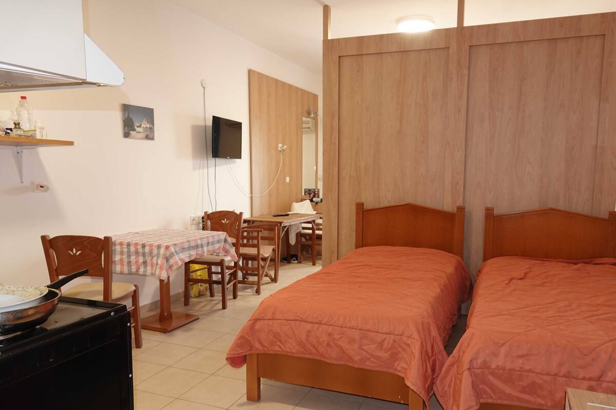 A room with two beds, a dining table with chairs, a TV, and a microwave.