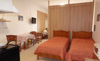Quarto com duas camas, uma mesa de jantar com cadeiras, uma televisão e um micro-ondas.