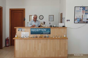 Uma mesa de recepção com uma placa que diz "RECEPTION AERIKO" e um relógio na parede.