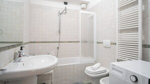 Un baño con lavabo, inodoro, ducha y toallero.