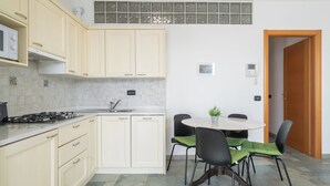 Una cocina moderna con gabinetes color crema, estufa a gas y un lavamanos. Hay un comedor con una mesa redonda y cuatro sillas.