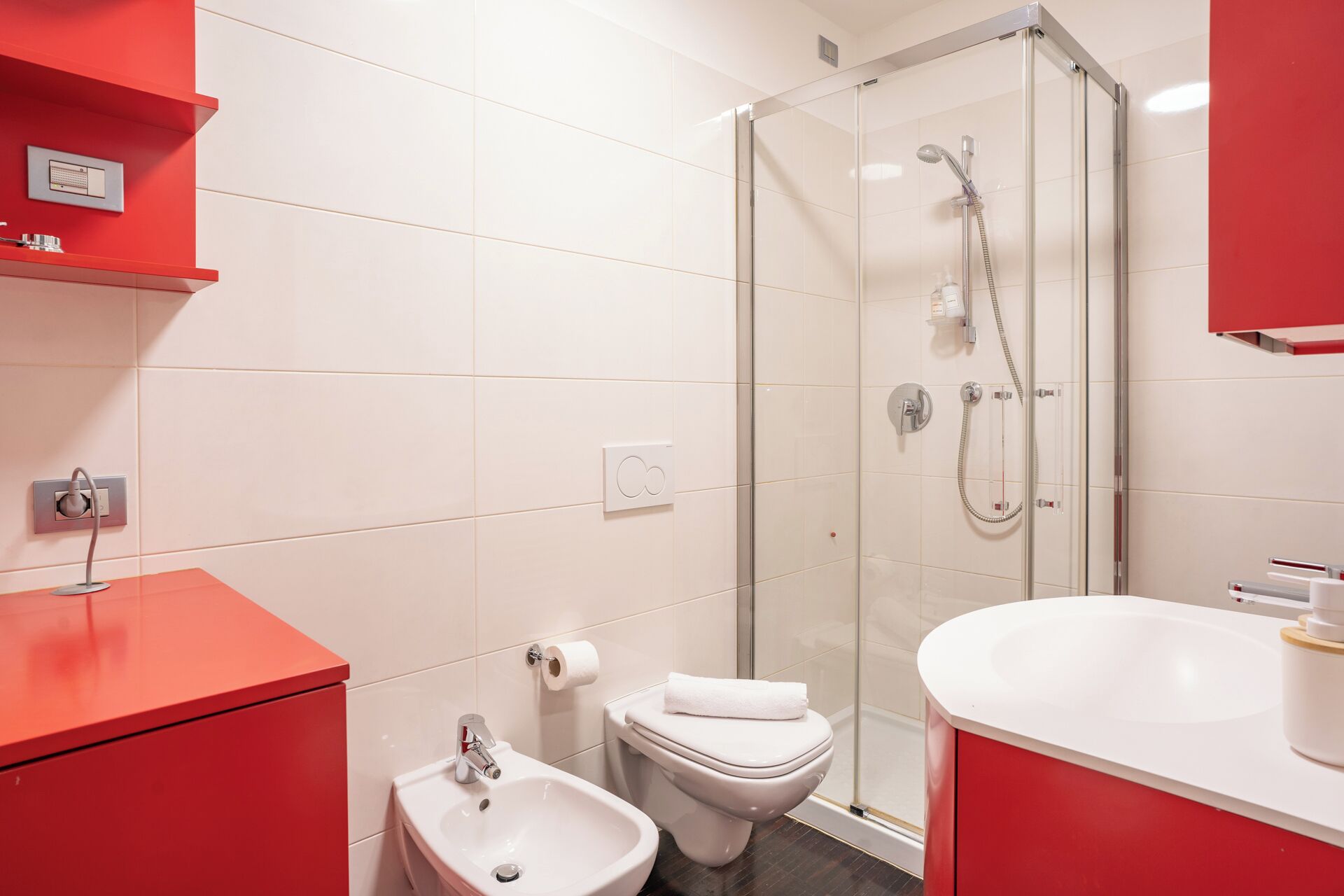 A modern bathroom with a glass-enclosed shower, a bidet, a toilet, and a sink.