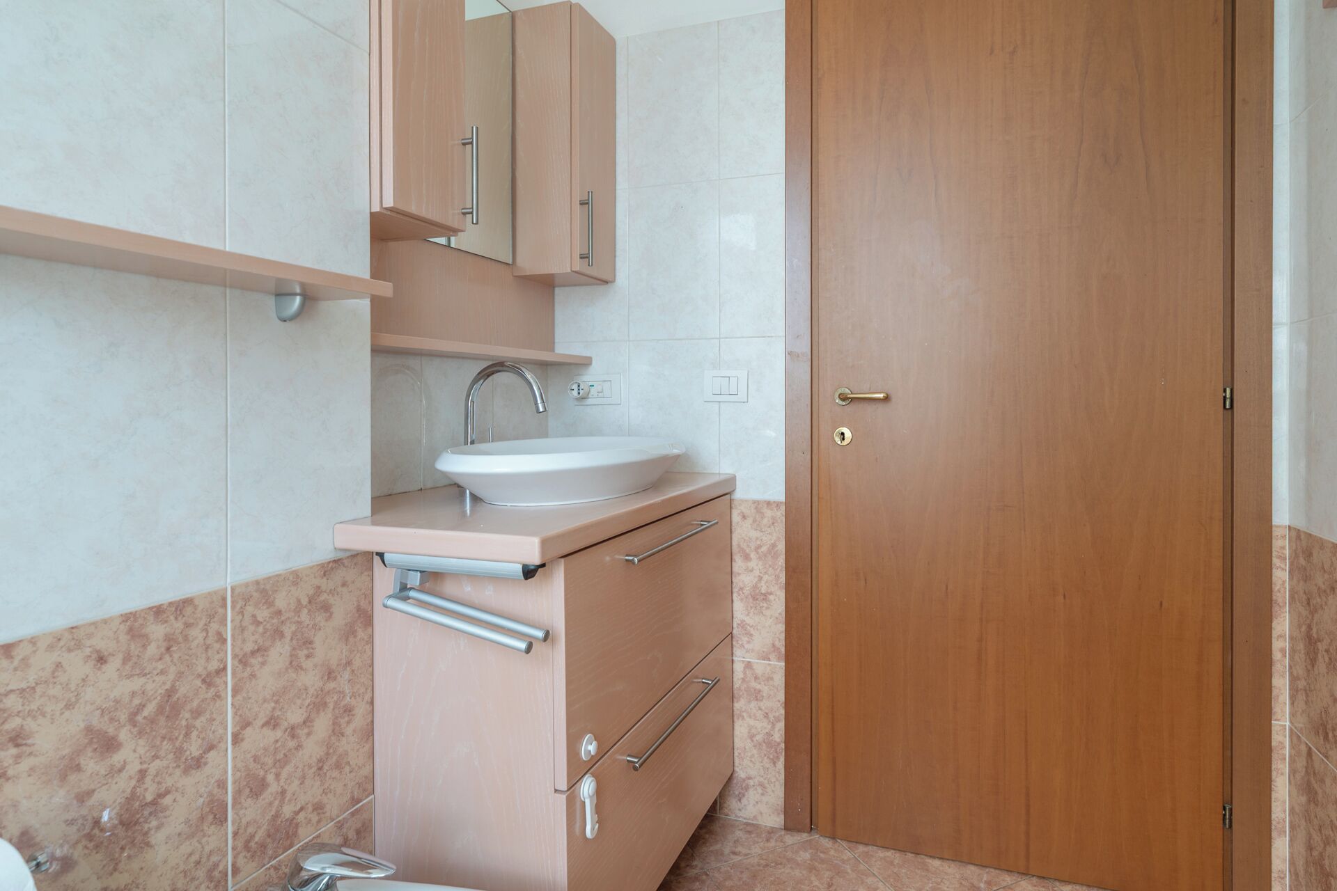 A bathroom with a sink, mirror, cabinet, and door.