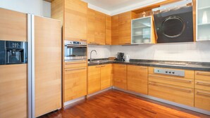 A modern kitchen with wooden cabinets, stainless steel appliances, and a marble countertop.