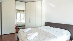 A modern bedroom with a large bed, a wardrobe, and a window with curtains.