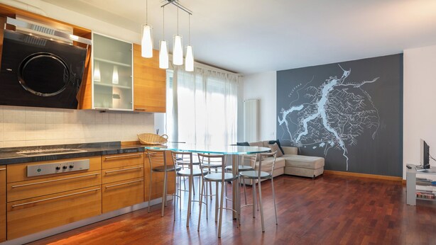 A modern kitchen with wooden cabinets, a glass dining table, and a large wall map.