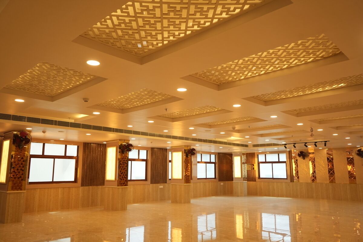 A spacious hall with a polished floor, large windows, and decorative ceiling panels.