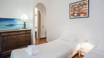 Una camera d'albergo con un letto, una cassettiera, un quadro e una lampada.