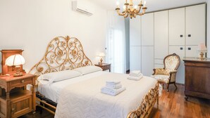 Een slaapkamer met een bed, een kroonluchter, een stoel en een kledingkast.