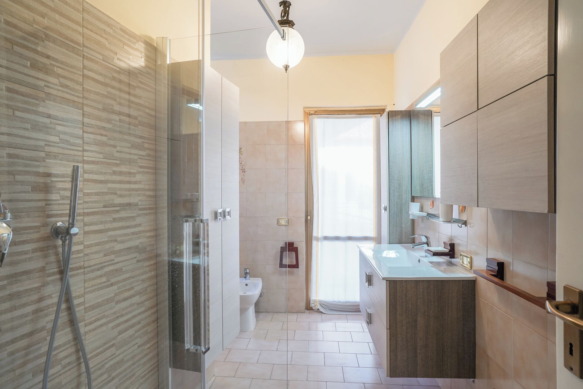 A modern bathroom with a glass shower enclosure, a sink with a mirror, and a toilet.