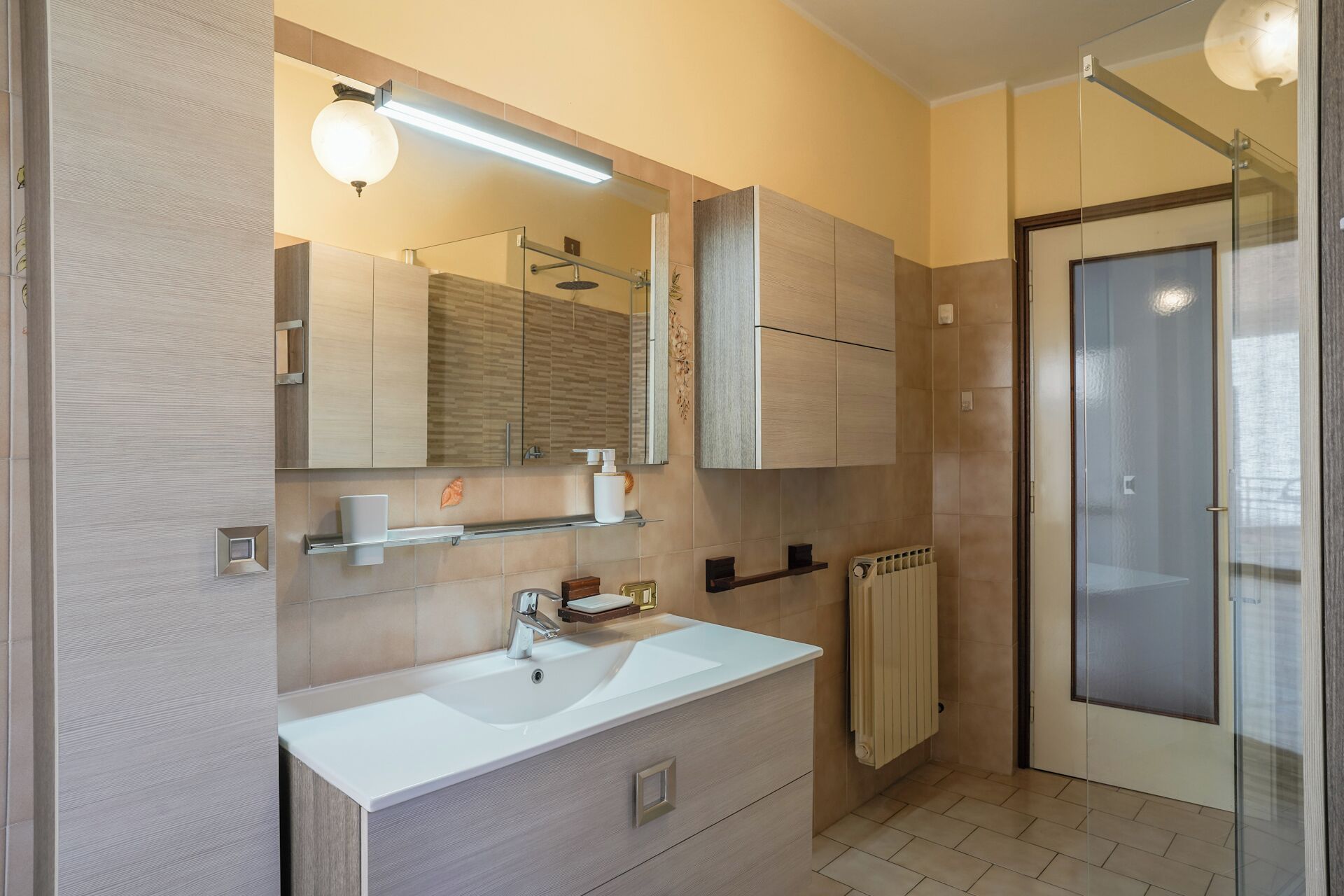 Une salle de bain moderne avec un lavabo blanc, un miroir et des meubles en bois.