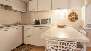 A compact kitchen with white cabinets, a microwave, a coffee maker, and a wicker basket on the counter. - Bellano Studio 2 - Studio Apartment, Sleeps 2 (Bellano)