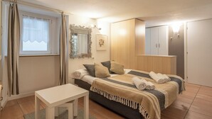 A bedroom with a bed, a small table, a mirror, and a wardrobe. - Bellano Studio 2 - Studio Apartment, Sleeps 2 (Bellano)