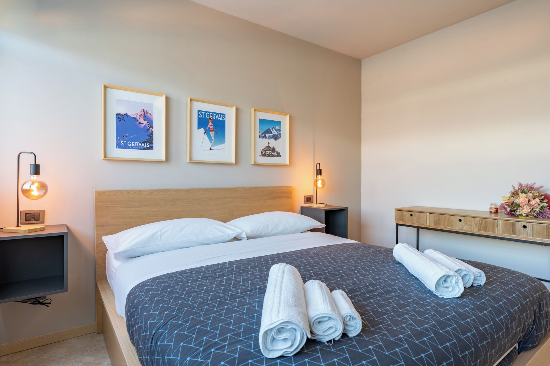 Ein Hotelzimmer mit einem Bett, zwei Nachttischen und drei gerahmten Bildern an der Wand.