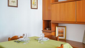 Ein Essbereich mit einem Tisch für zwei Personen, zwei gerahmten Pflanzenbildern an der Wand und einer Holzeinrichtung über dem Tisch.