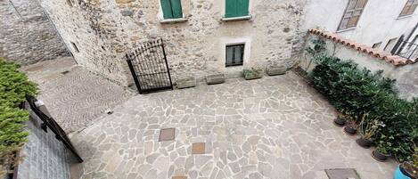 A courtyard with stone flooring, a metal gate, and potted plants.