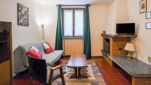 Ein gemütliches Wohnzimmer mit einer Couch, einem kleinen Tisch, einem Kamin und einem Fernseher.