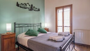 A bedroom with a bed, two nightstands, a window with curtains, and a wall decoration.