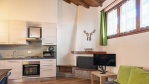 A compact kitchen with modern appliances, a fireplace, and a cozy seating area with a TV. - La Corte della Casera - Verbena (Cremeno)