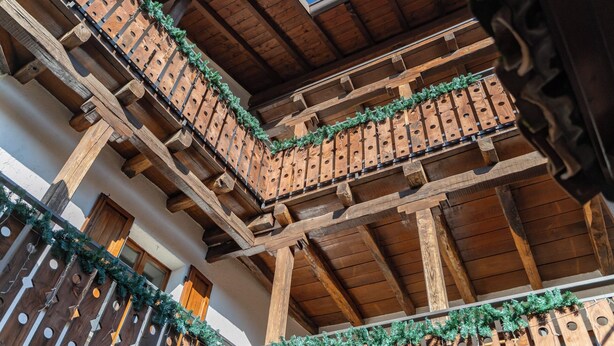 A traditional wooden balcony with a wooden railing and a decorative garland. - La Corte della Casera - Verbena (Cremeno)