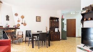 Una sala de estar con chimenea, un comedor con sillas, un televisor y una estantería.