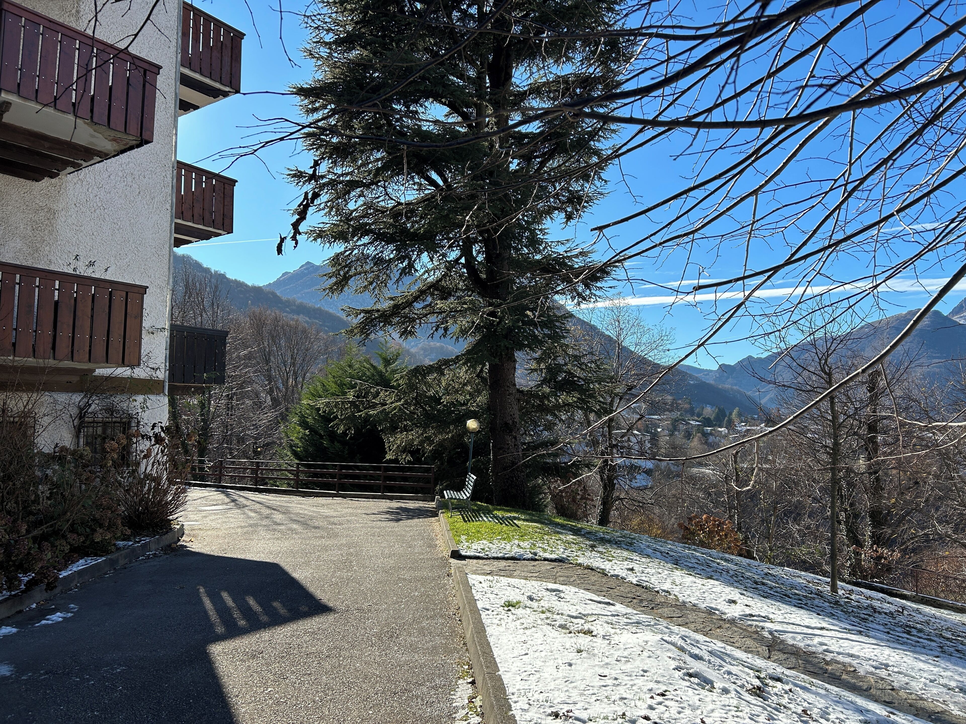 A building with balconies, a snow-covered slope, and a mountain view.