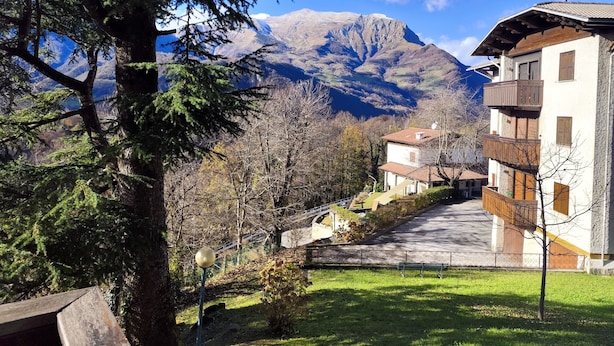 Vista de la montaña con un edificio que tiene balcones y un sendero pavimentado.